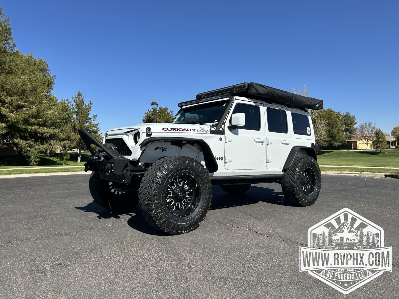 White 2018 Jeep Wrangler Unlimited overlanding rental with rooftop tent closed, front three-quarter view