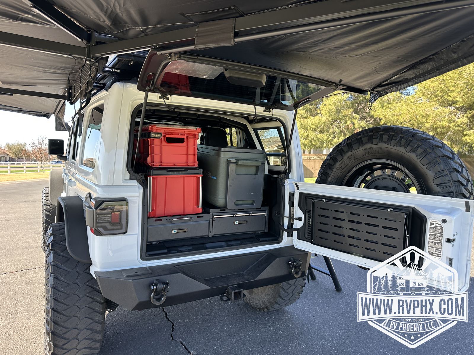 Tailgate open under the awning showing the rear drawer system and camp storage